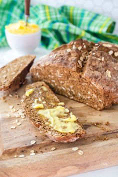 a loaf of bread sitting on top of a wooden cutting board next to sliced bread