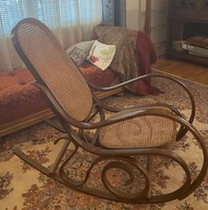 a rocking chair sitting on top of a rug next to a window