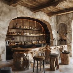 a bar with stools and bottles on the shelves in an old stone walled room