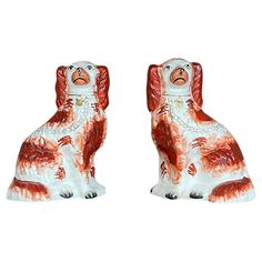 two red and white ceramic dog figurines sitting side by side on a white background