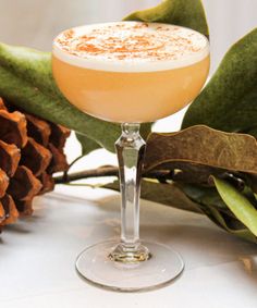 a drink sitting on top of a table next to pine cones