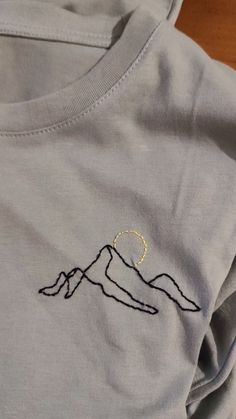 a close up of a person's t - shirt with mountains embroidered on it