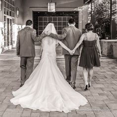 a bride and groom walking down the street with their arms around each other as they hold hands