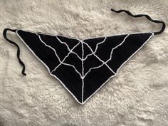 a black and white triangle shaped piece of cloth on a furry surface with string attached to it