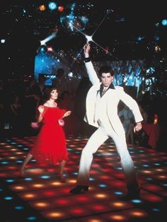 a man and woman dancing on a dance floor with disco lights in the back ground