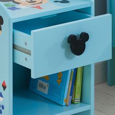 a blue drawer with mickey mouse stickers on the drawers and books in front of it