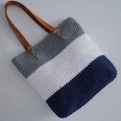 a crocheted bag is sitting on the floor next to a brown leather handle