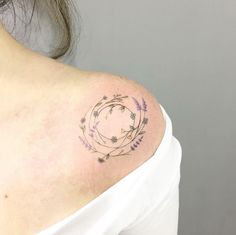 a woman's shoulder with a circle tattoo on the left side of her upper arm