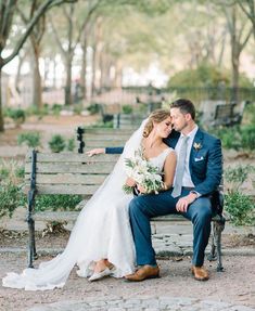 a bride and groom sitting on a park bench