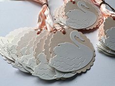 several tags with swans on them are tied to a pink ribbon and placed next to each other