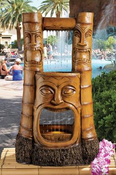 a wooden statue with a water fountain in front of it and people sitting around the pool