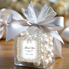 a square glass box with pearls and a bow on top that says thank you in the center