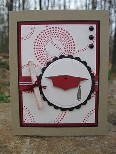 a graduation card with a red cap and tassel on the front, sitting on a rock