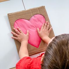 a child is making a heart out of cardboard