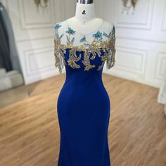 a blue evening gown with gold detailing on the shoulders and shoulderline is displayed in front of a mannequin