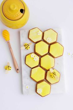 cookies decorated with bees and honeycombs are on a marble board next to a wooden spoon