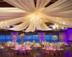 a banquet hall with tables and chairs covered in white draping