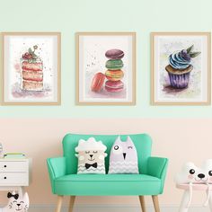 three framed pictures hang on the wall above a green chair with two cats sitting in front of it