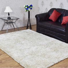 a living room with a black leather couch and white rug