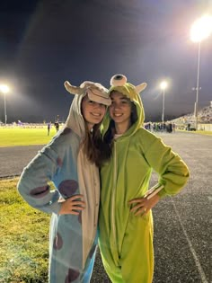 two women dressed in costumes posing for a photo at a football game on the field