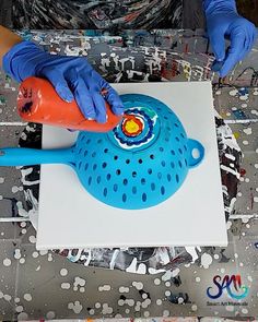 a person in blue gloves and rubber gloves painting a piece of art on a table