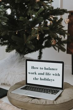 a laptop computer sitting on top of a pillow next to a christmas tree with the words how to balance work and life with the holidays