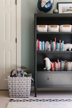 a bookshelf with many books and stuffed animals on it next to a door