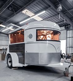 an old fashioned trailer is parked in a garage with its door open to show the interior