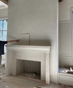 a man standing next to a fireplace in a room with no one on the floor