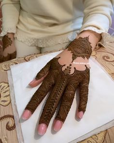 a woman's hands with hennap on top of a white cloth covered table