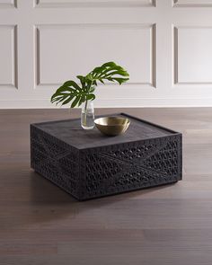 a plant in a vase sitting on top of a black box with a gold bowl