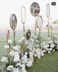 white flowers and candles are lined up in front of an outdoor ceremony area with mirrors