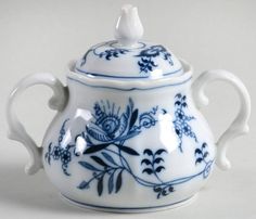 a blue and white tea pot with handles on the lid is sitting in front of a plain background