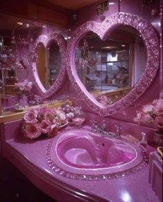 a pink bathroom with heart shaped mirrors and flowers on the counter top, in front of a large mirror