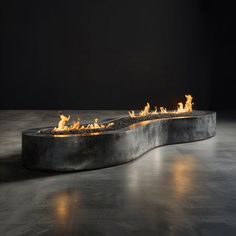 a fire pit sitting on top of a cement floor next to a black wall with lights