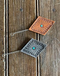 two small square tiles with turquoise stones on them sitting on a wooden surface next to a string