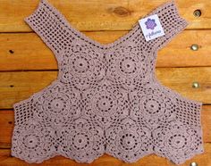 a crocheted top is displayed on a wooden surface