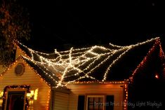 a house covered in christmas lights at night with the roof lit up and decorations on it