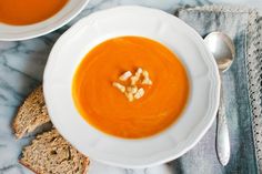 there is a bowl of soup with bread on the side