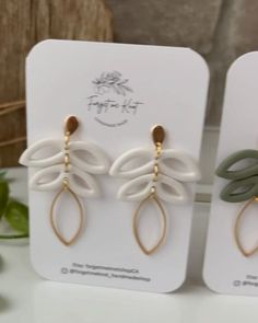 two pairs of white and green earrings on display