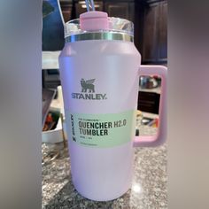 a pink water bottle sitting on top of a counter next to a cup with a straw in it