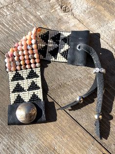 a black and white beaded horse bridle on a wooden floor with a metal bell