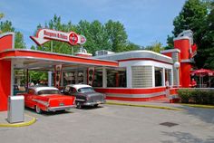 two old cars are parked in front of a gas station with red and white paint