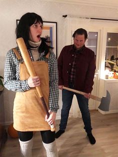 a woman holding a baseball bat in her hands and another man standing behind her with his mouth open