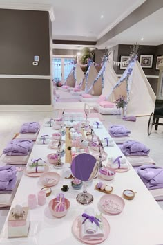 a table set up for a baby shower with purple decorations and pink plates on it