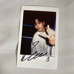 an autographed photo of a young man holding a peace sign in his right hand