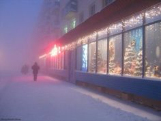 a person walking down a snowy street in front of a store