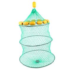 a green wire basket filled with oranges sitting on top of a white wall next to a yellow object