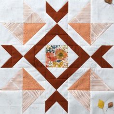 an orange and white patchwork quilt with flowers in the center, on top of it