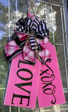 a pink door hanger with black and white ribbon that says i love you on it